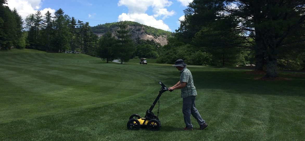 Technician using GPR at golf coarse in Cashiers, NC - rock cliff in background