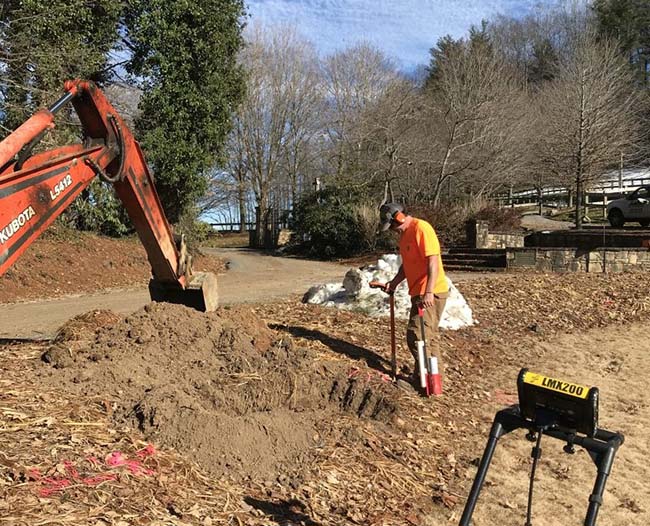 Technician using electro-acoustic equipment to locate water line