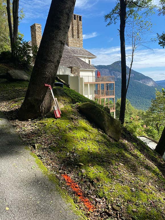 Mountainside home with view showing orange paint mark on ground next to road